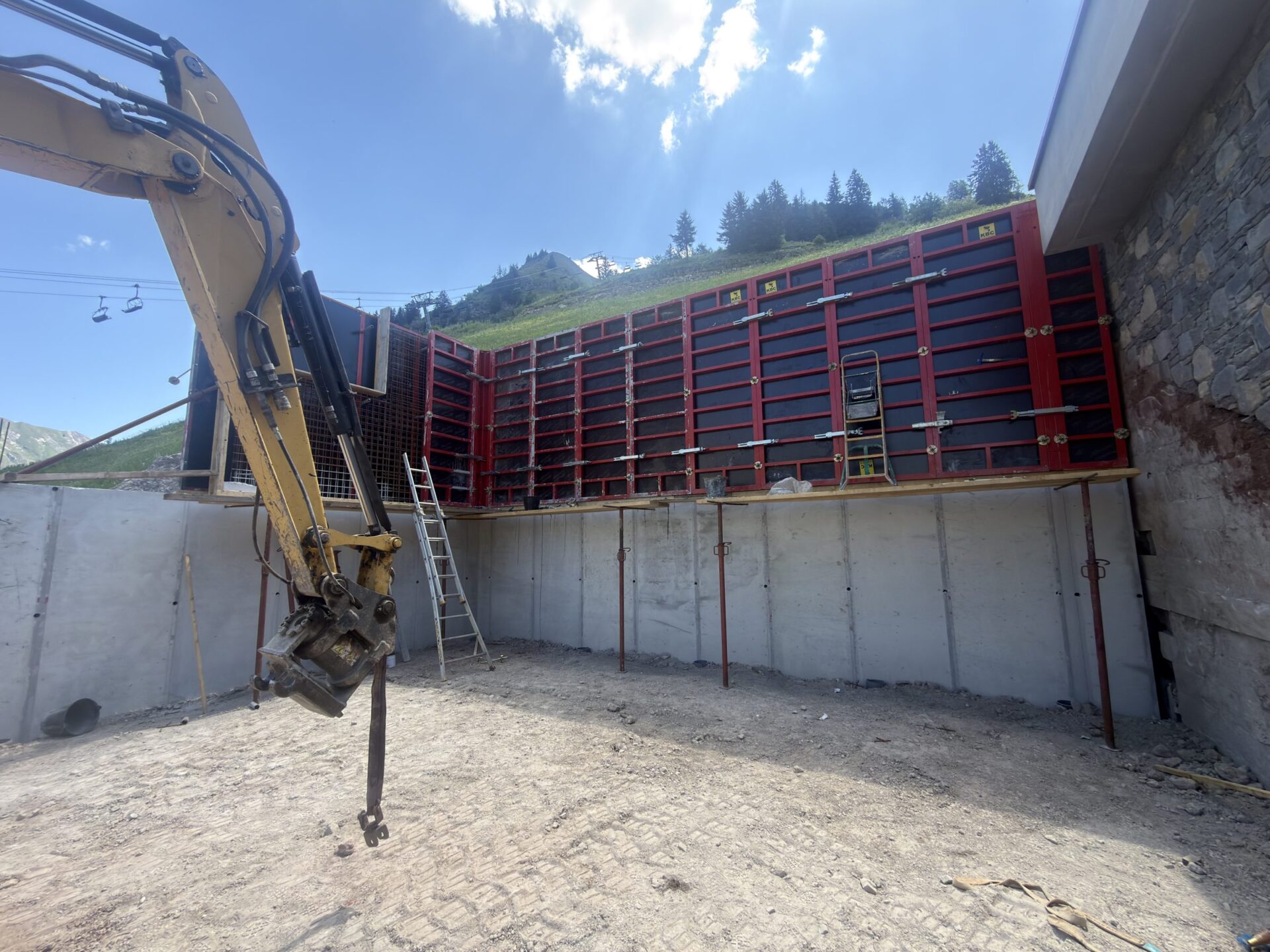 Mur de soutènement en béton coffré et pelle mécanique